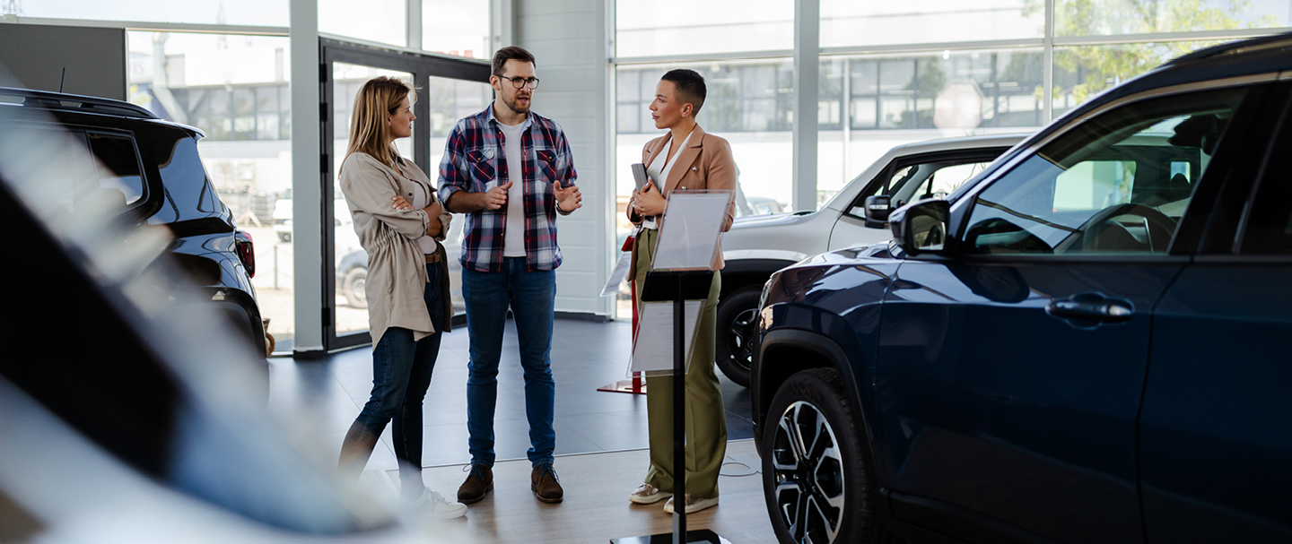 A couple speaking to a salesperson inside a car dealership