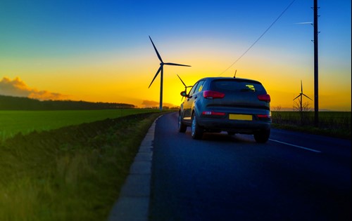 EV on road with wind turbine