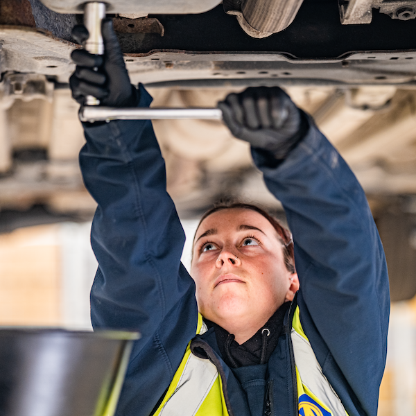 Female mechanic working underneath car