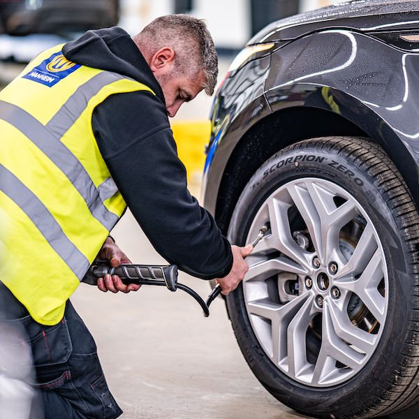 Male mechanic pumping air into car tyre