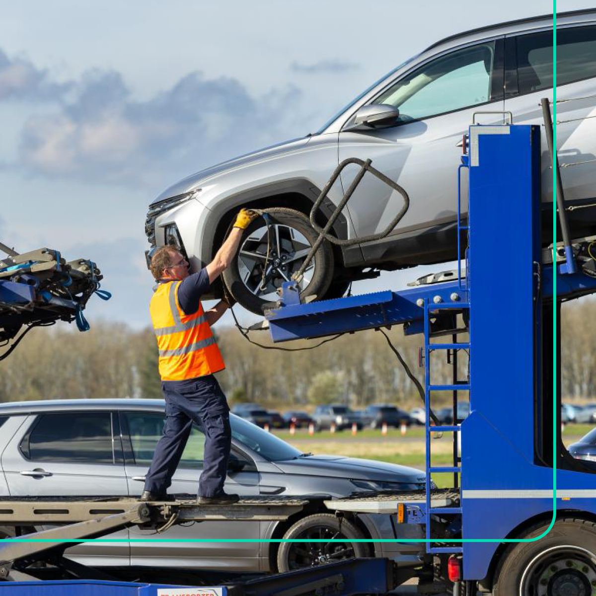 Worker securing SUV onto vehicle transporter for efficient fleet logistics.