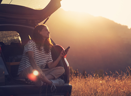 Woman looking to the future from the boot of her car